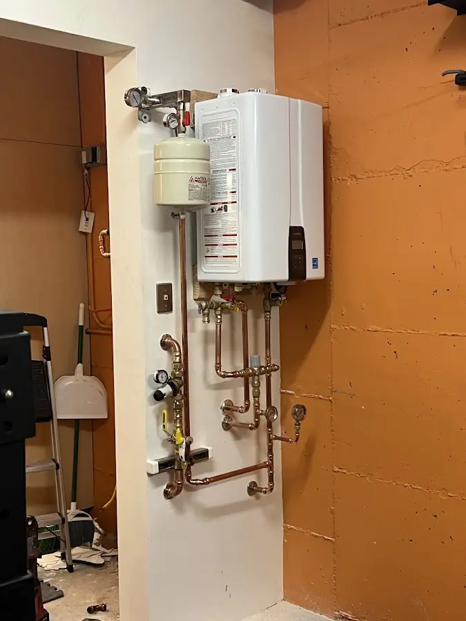 Plumbing technician inspecting water heater connections in Amherst